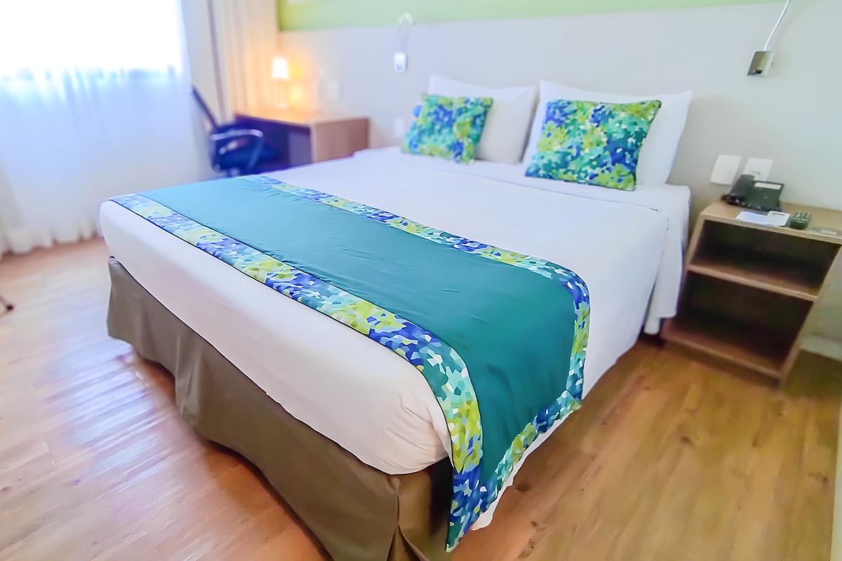 Una habitación de hotel con cama, mesita de noche, silla y escritorio.