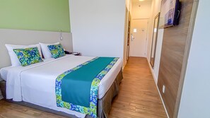 A hotel room with a bed, a bedside table, a chair, and a television mounted on the wall. - Blue Tree Towers Valinhos (Valinhos)