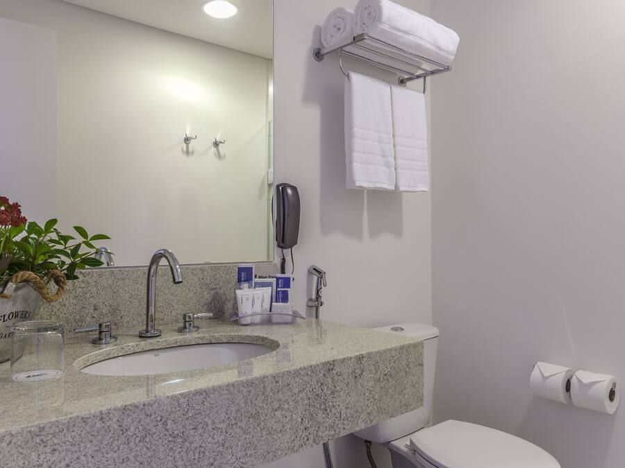 Un baño moderno con encimera de granito, un lavabo, un espejo, un perchero y un inodoro.