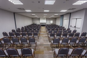 A conference room with rows of chairs, a projector screen, and a whiteboard. - Blue Tree Towers Valinhos (Valinhos)
