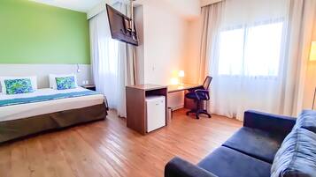 Una habitación de hotel con cama, escritorio, silla y sofá.