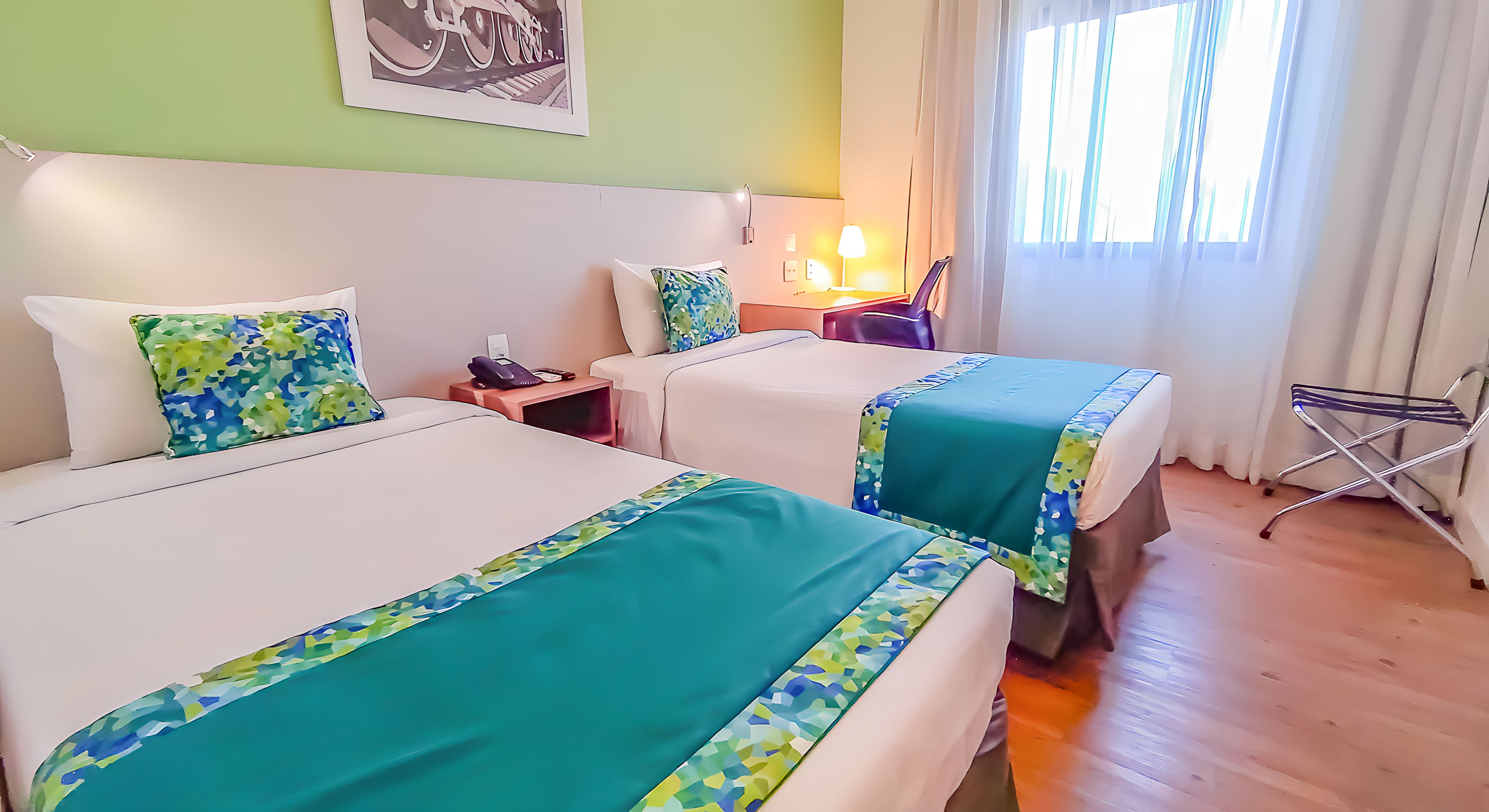 Une chambre d’hôtel avec deux lits, une table de chevet, une lampe et une chaise.