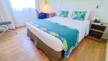 A hotel room with a bed, a bedside table, a lamp, and a chair.