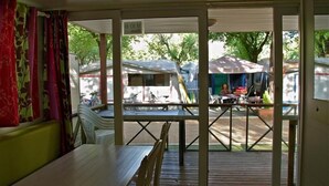 Een overdekt zitgedeelte buiten met een tafel en stoelen, een uitzicht op de straat en een bord waarop staat dat er maximaal 10 personen toegestaan zijn.