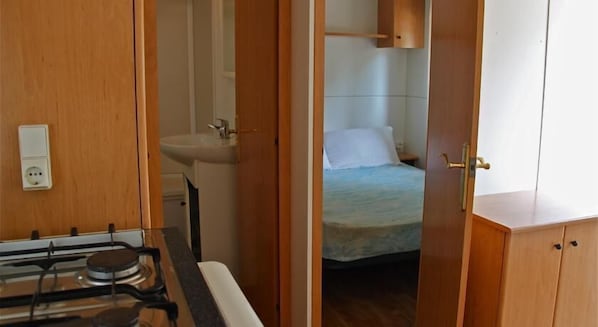A compact room with a kitchenette, a bed, and a bathroom.
