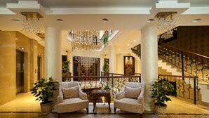A spacious lobby with two armchairs, a chandelier, and a staircase with ornate railings. - Black Bird Thermal Hotel & Spa (Termal)