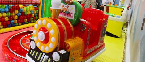 A colorful children's ride with a train theme, including a red and yellow locomotive and a green car.