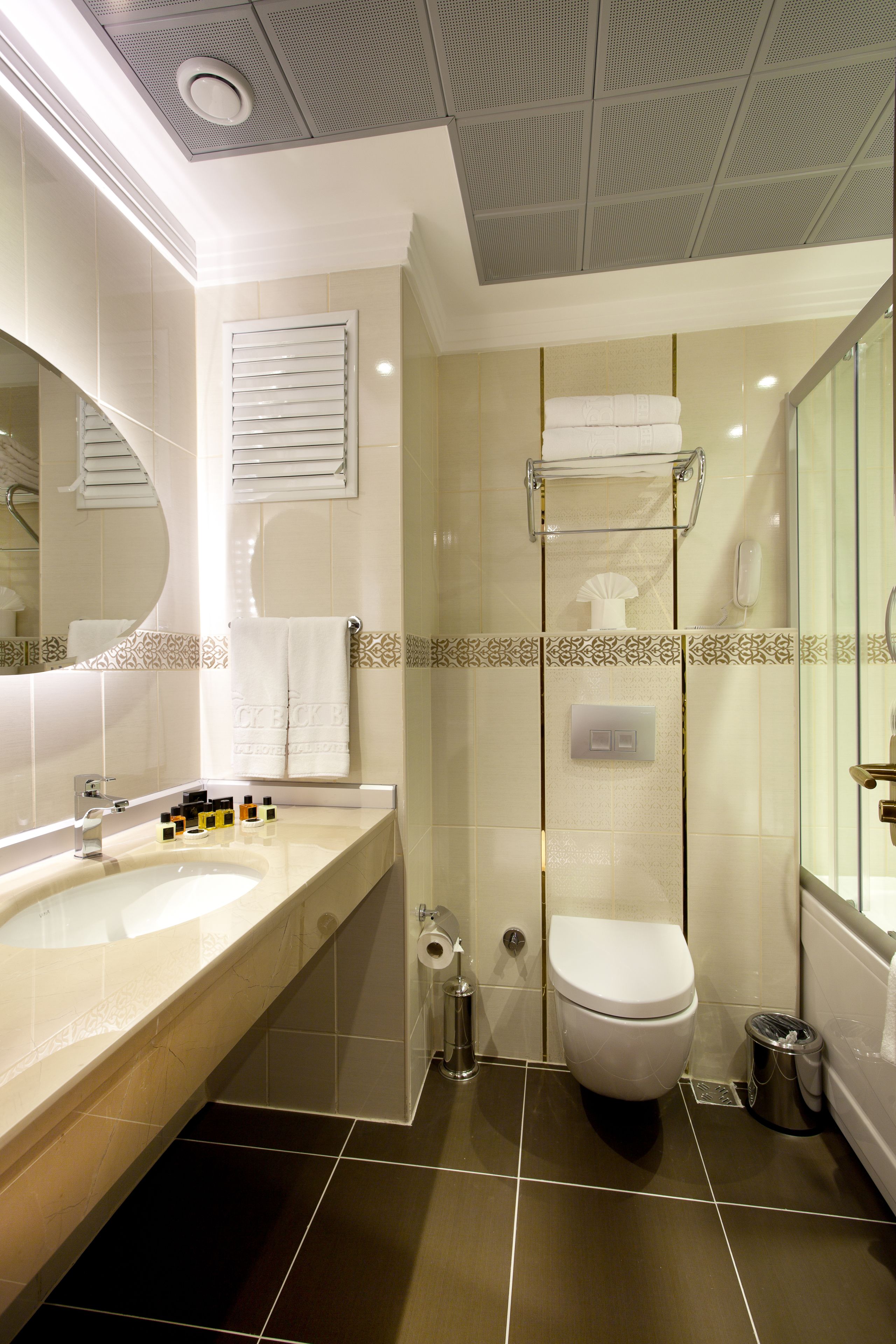 Un baño moderno con un lavamanos grande, espejo, inodoro y ducha.