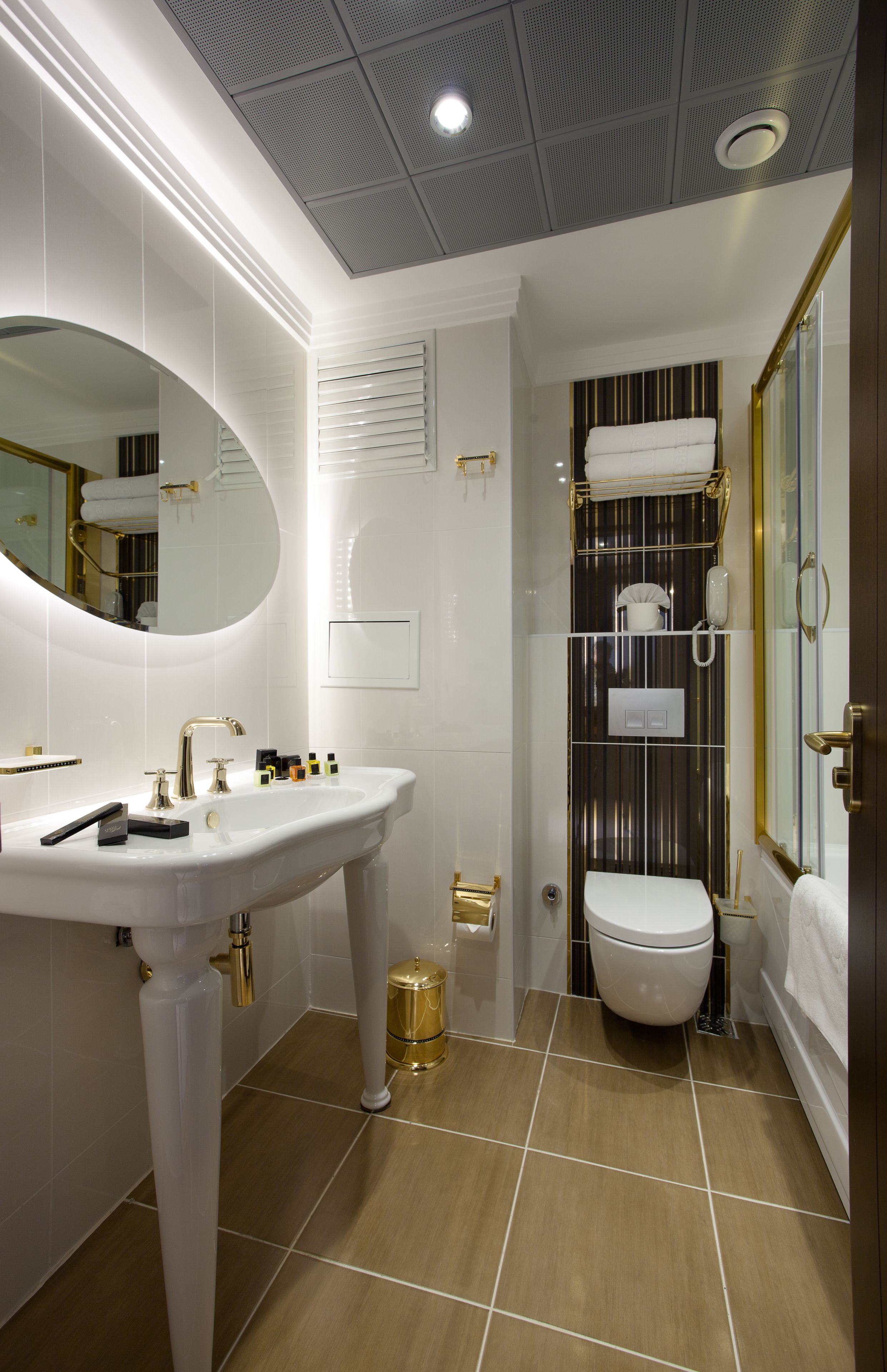 A modern bathroom with a pedestal sink, a toilet, and a shower area.