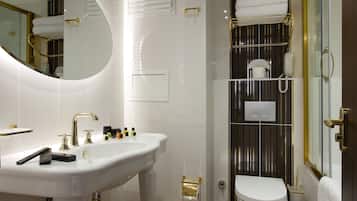 A modern bathroom with a pedestal sink, a toilet, and a shower area.