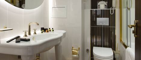 A modern bathroom with a pedestal sink, a toilet, and a shower area.