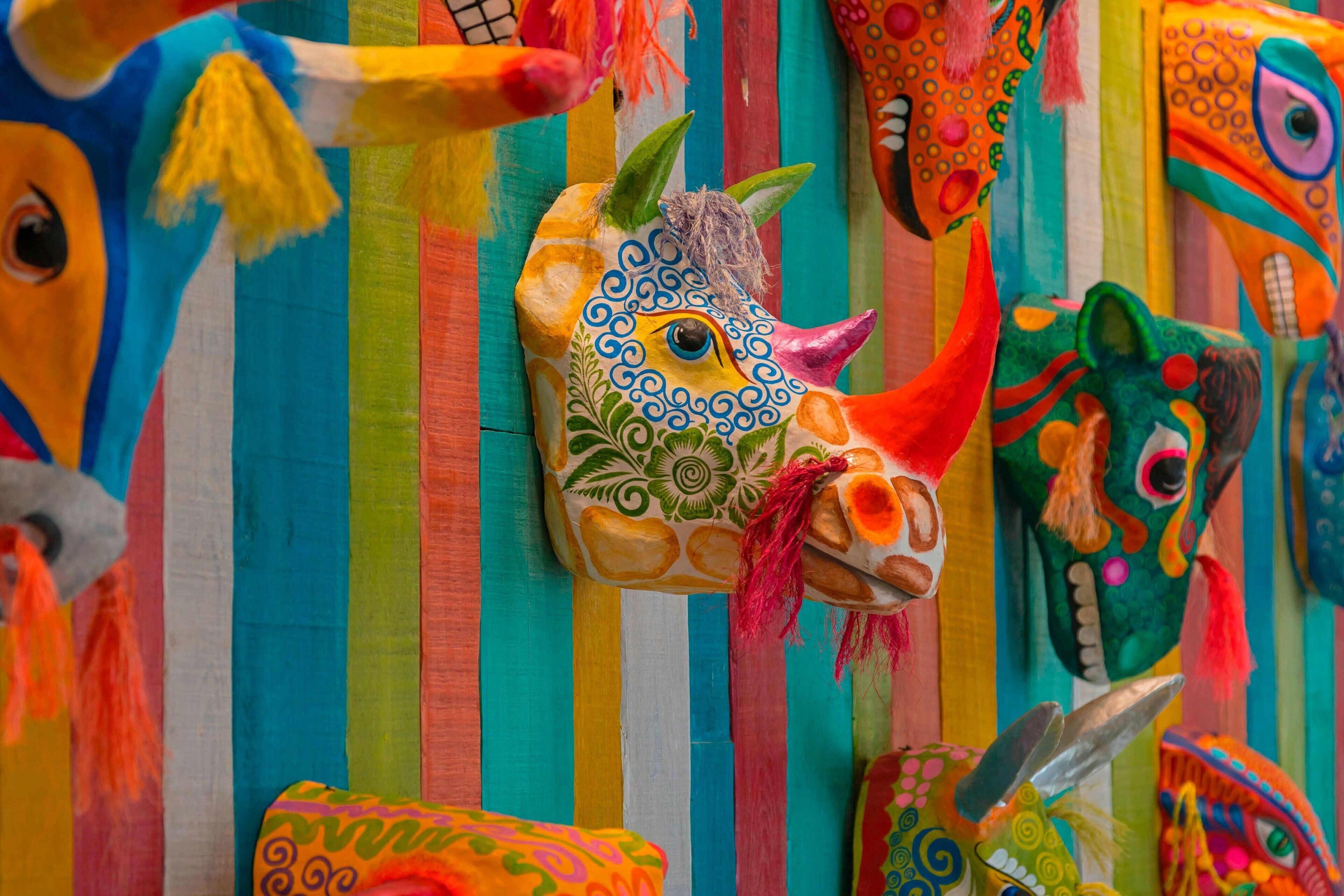 Un mural colorido con diversas máscaras y patrones vibrantes.