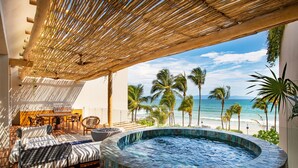 Una terraza en la azotea con jacuzzi, mobiliario exterior y vistas al océano.