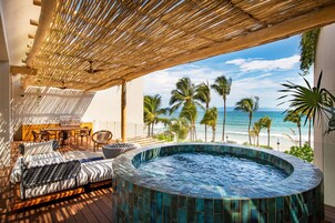 Una terraza en la azotea con jacuzzi, mobiliario exterior y vistas al océano.