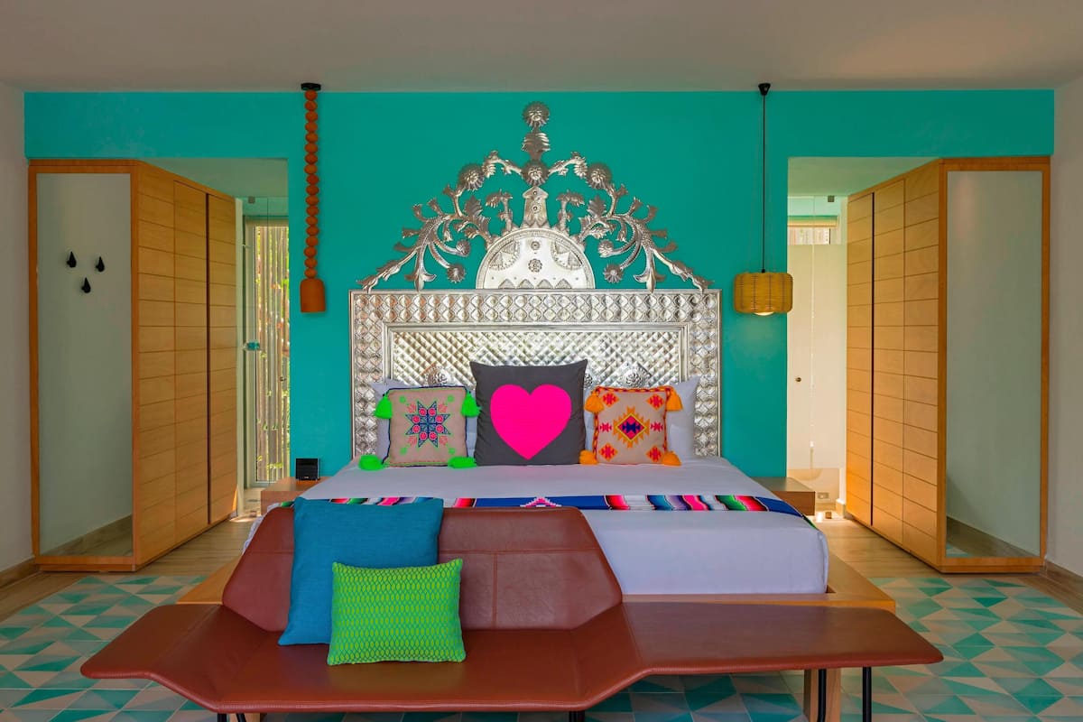 Habitación de hotel con una cama grande, cabecero de madera y vistas al exterior.