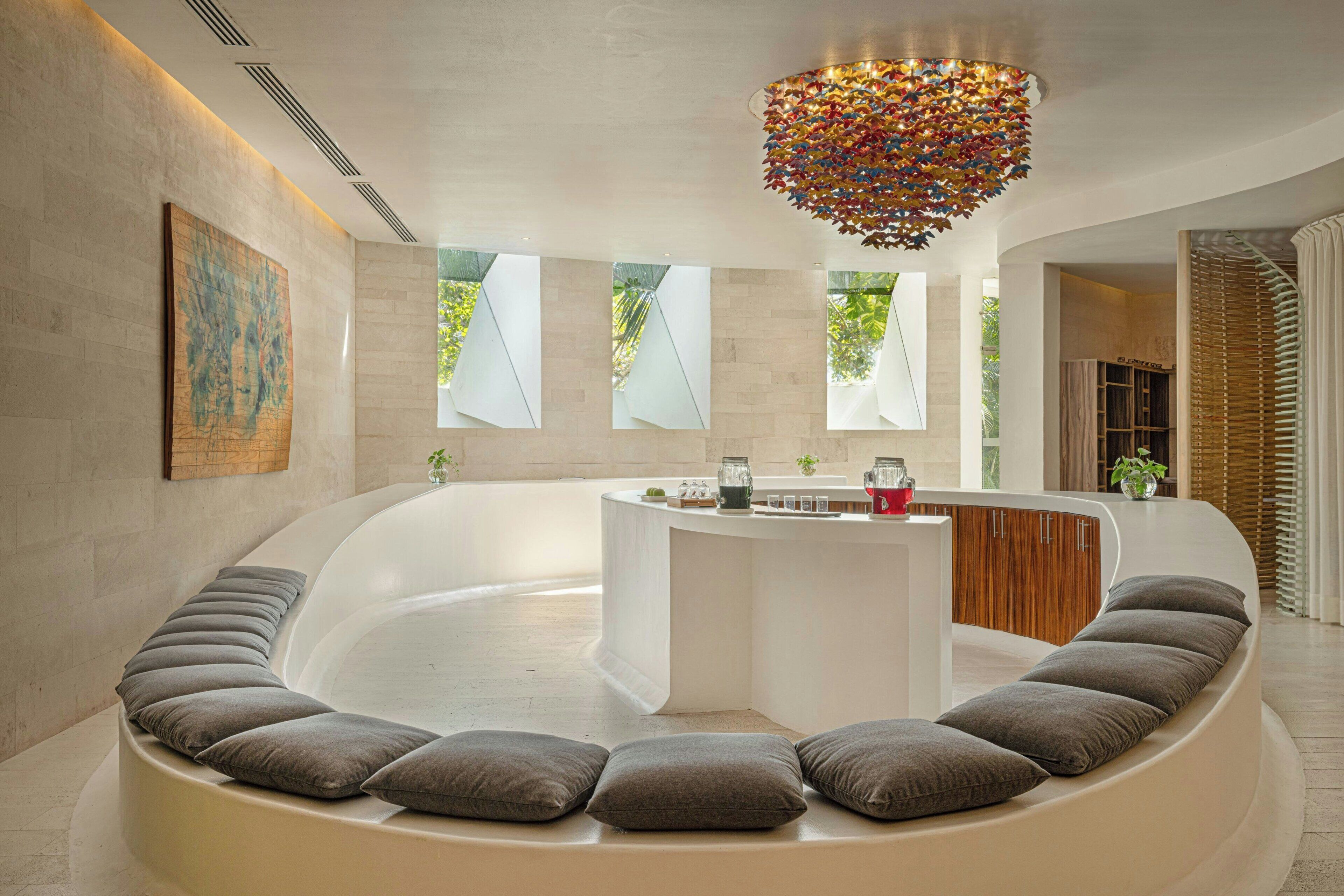 A modern spa area with a curved seating arrangement, a central water feature, and a decorative ceiling light.