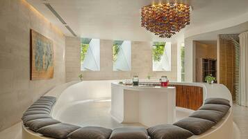 Een moderne spa met een gebogen zithoek, een fontein in het midden en een decoratieve plafondlamp.