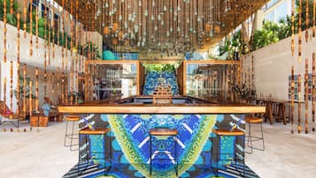 Un área de bar moderna con suelo de mosaico, muebles de madera y lámparas colgantes.