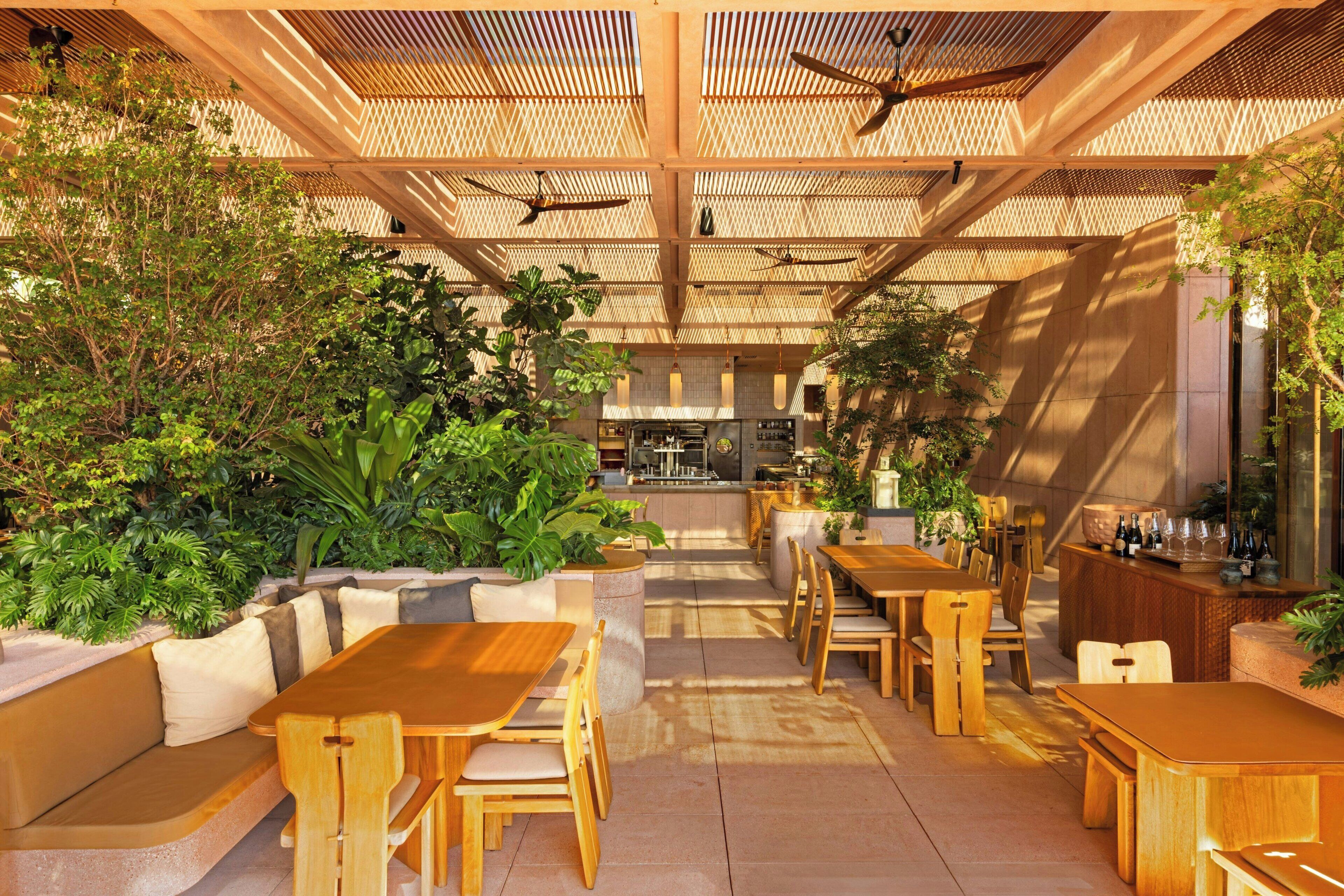 An indoor dining area with wooden tables and chairs, a bar area, and a kitchen in the background.