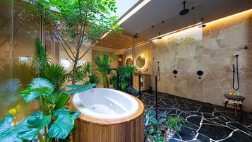 Un baño moderno con suelo de piedra, una bañera de madera y varias plantas.