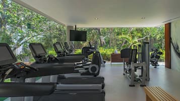 Un gimnasio moderno con cintas de correr, máquinas de pesas y una pantalla de televisión.