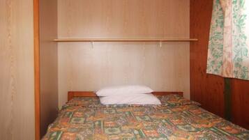 Habitació petita amb un llit individual, un capçal de fusta i un edredó estampat.