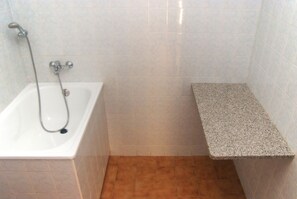 A bathroom with a bathtub, a shower, and a granite countertop.