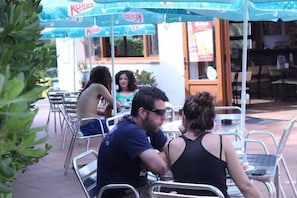 An outdoor dining area with metal chairs and tables, covered by blue umbrellas with the 'Kahlua' logo.