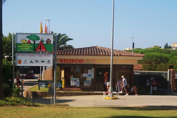 A reception area with a sign for Camping Internacional Palamos and a group member badge.