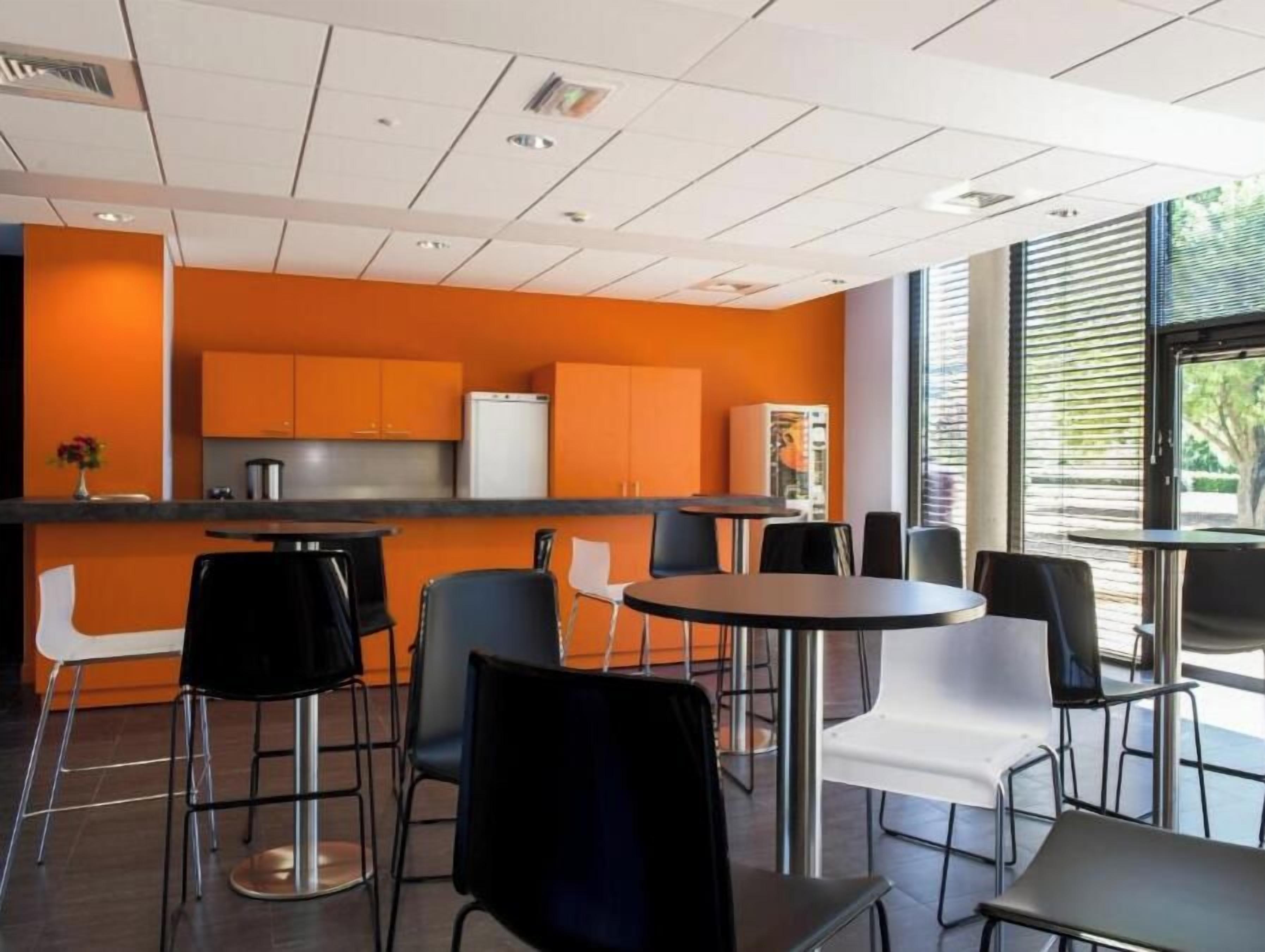 A modern interior with a kitchen area, dining tables, and chairs.