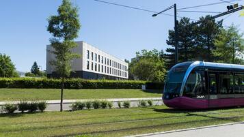 A modern train station with a sleek purple train, a clear sky, and a building with large windows in the background.