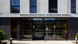 Un edifici modern amb un rètol que diu "MAISON INTERNATIONALE - INTERNATIONAL HOUSE".