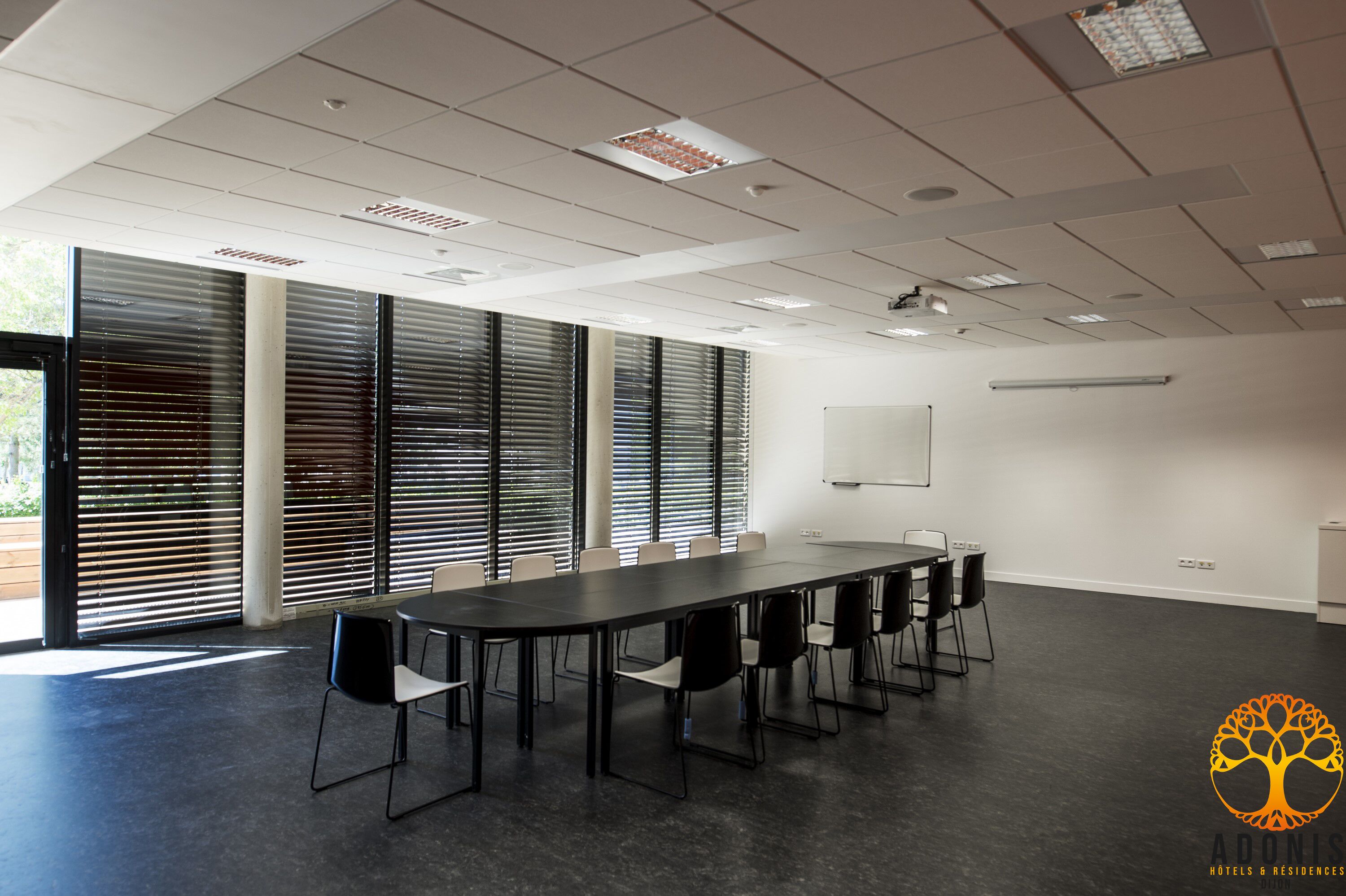 A conference room with a long table, chairs, and large windows with blinds.