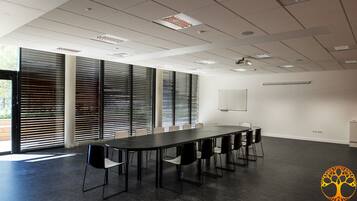 A conference room with a long table, chairs, and large windows with blinds.