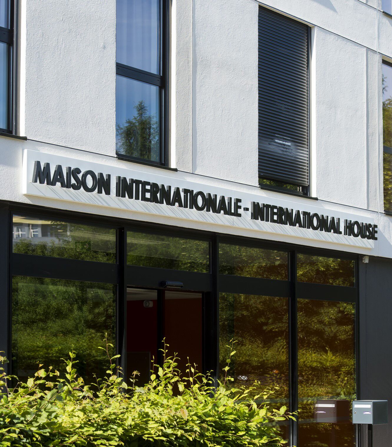 A building with a sign reading "MAISON INTERNATIONALE - INTERNATIONAL HOUSE".