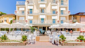 A hotel with multiple balconies, outdoor seating, and a clear sky. - Hotel Bellariva (Jesolo)