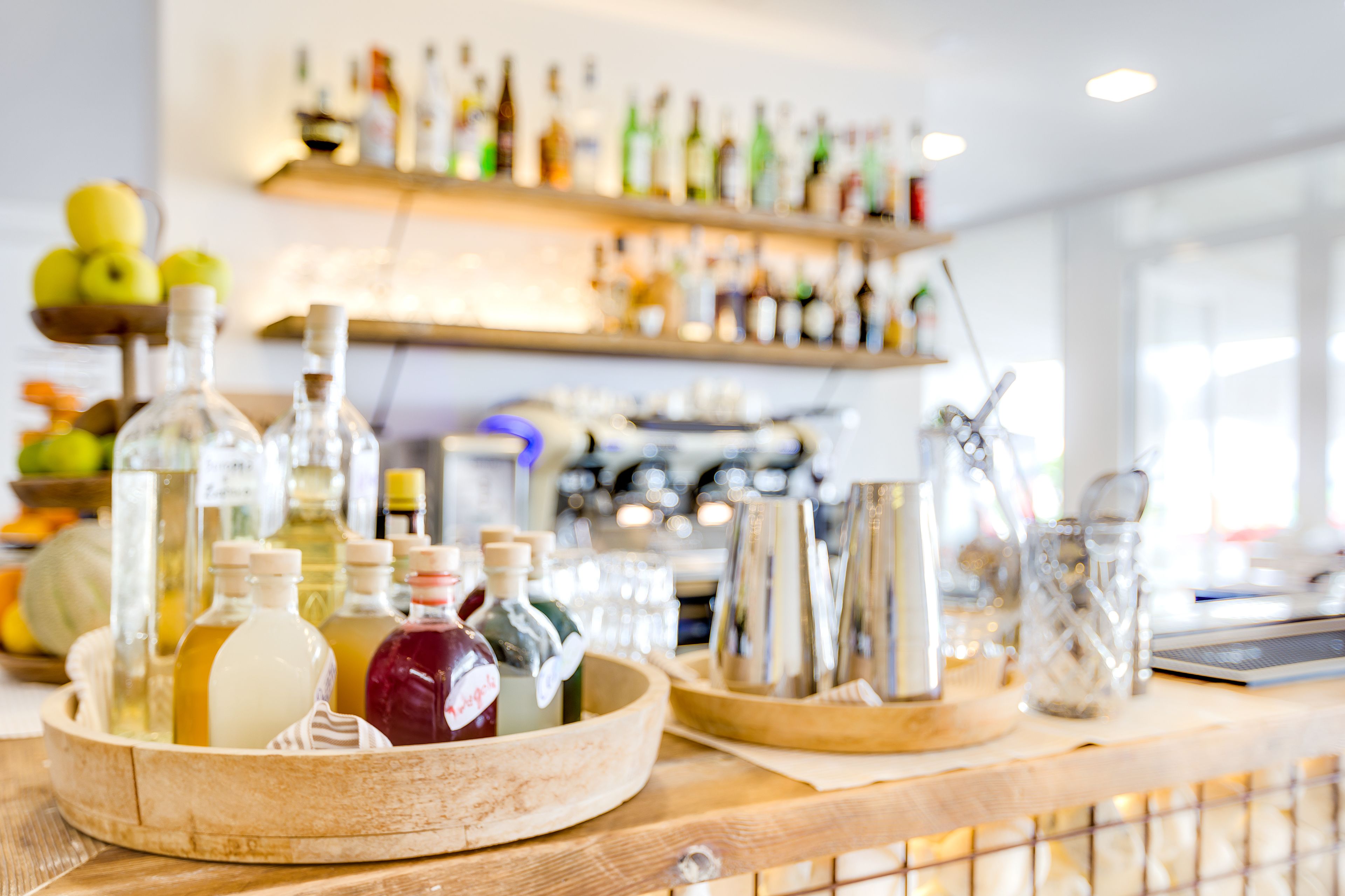 A bar area with various bottles and glasses on wooden trays.
