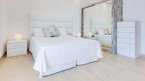 A modern bedroom with a large bed, bedside tables, a dresser, and a mirror. - Hotel Bellariva (Jesolo)