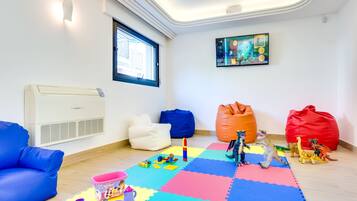 Camera adatta ai bambini, con divano blu, tappetino colorato e dinosauri giocattolo.