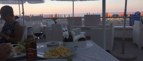 Comedor con mesas, sillas y sombrillas con vista a la playa.