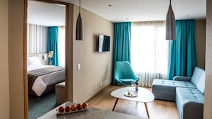 Une chambre d’hôtel comprenant un lit, un canapé, une télévision et un coin repas avec une table et des chaises.