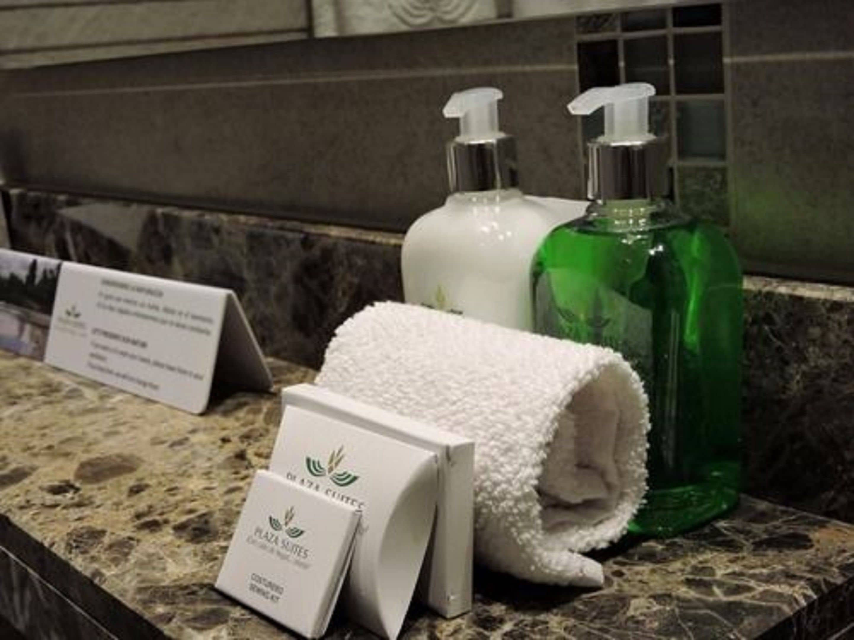 Un meuble-lavabo dans une salle de bain, avec des articles de toilette, une serviette blanche et un panneau.
