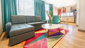 A modern living room with a sectional sofa, a round coffee table, and a colorful rug. - Hotel Plaza Suites (Bogotá)