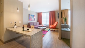 Un salon moderne comprenant un canapé, une table à manger et un coin cuisine avec un téléphone et une bouteille de vin.