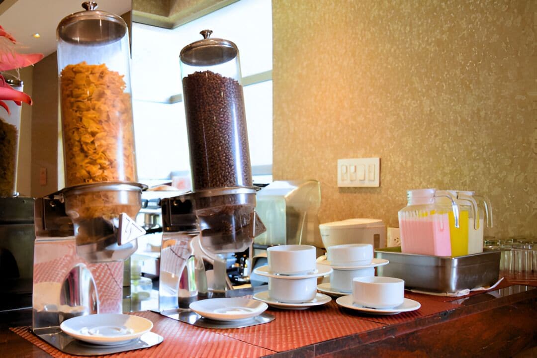 A buffet setup with a coffee machine, a juice dispenser, and various bowls and plates.