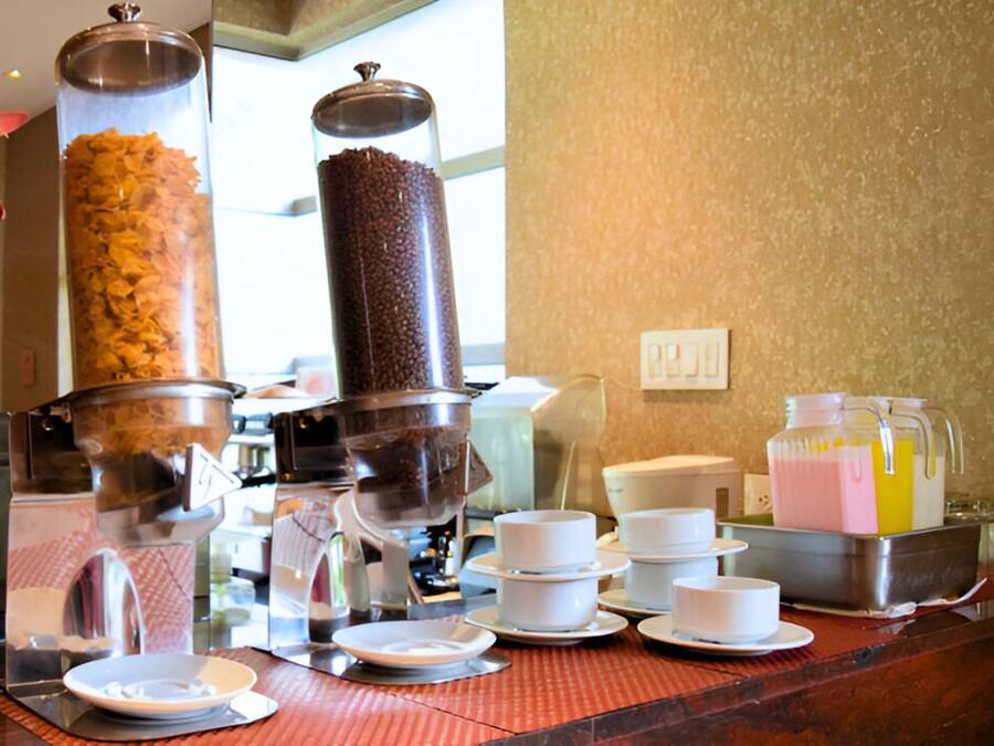 A buffet setup with a coffee machine, a juice dispenser, and various bowls and plates.