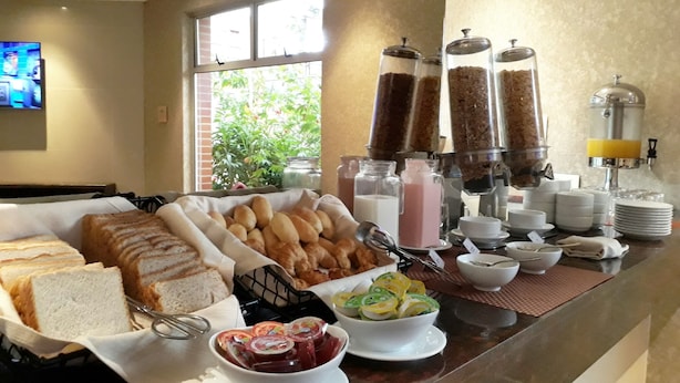 Un buffet de petit-déjeuner comprenant du pain, des viennoiseries et diverses boissons.