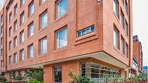 Un immeuble à plusieurs étages, construit en briques, avec un toit plat et de grandes fenêtres.