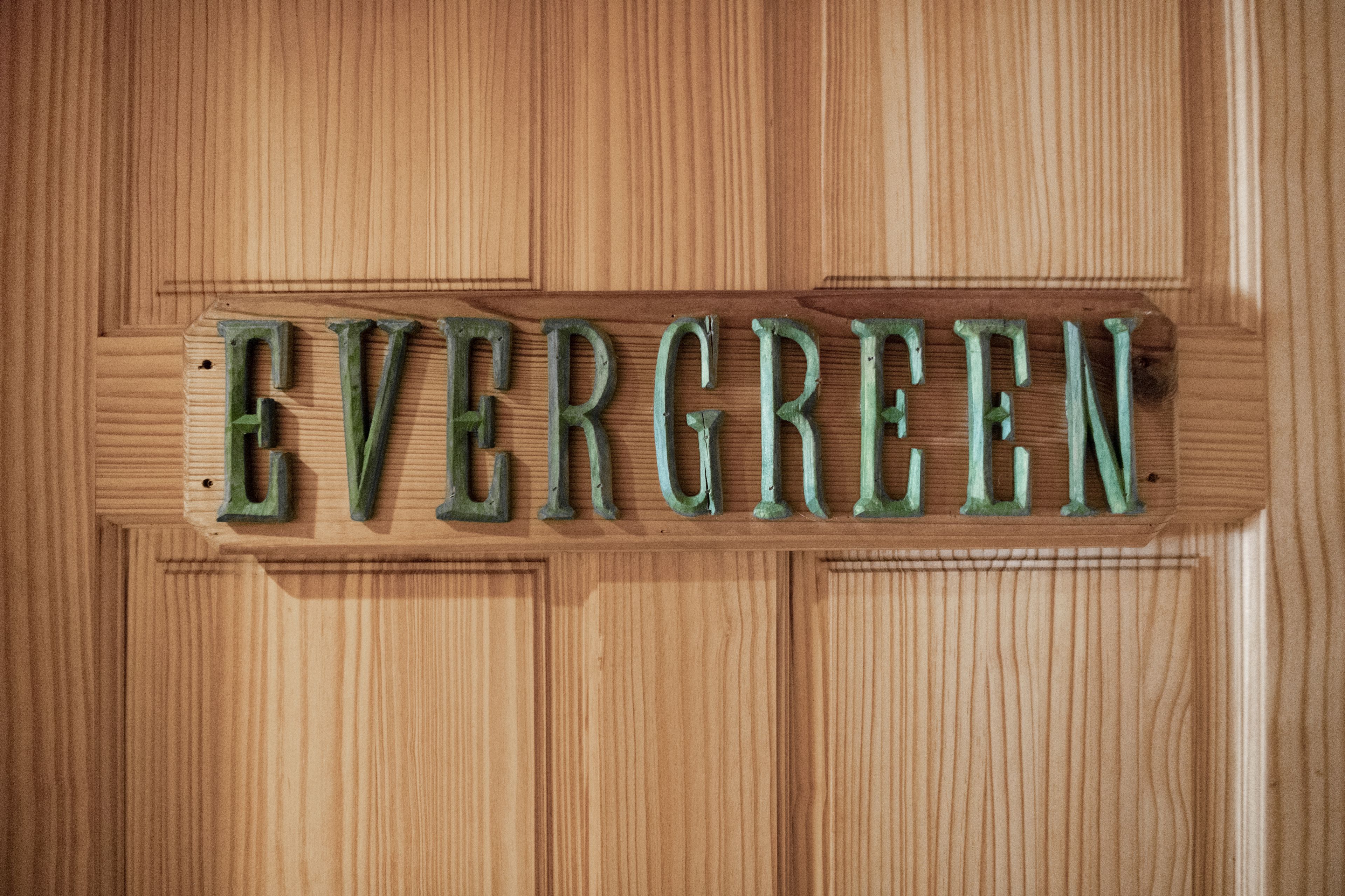 A wooden sign with the word "EVERGREEN" in capital letters.