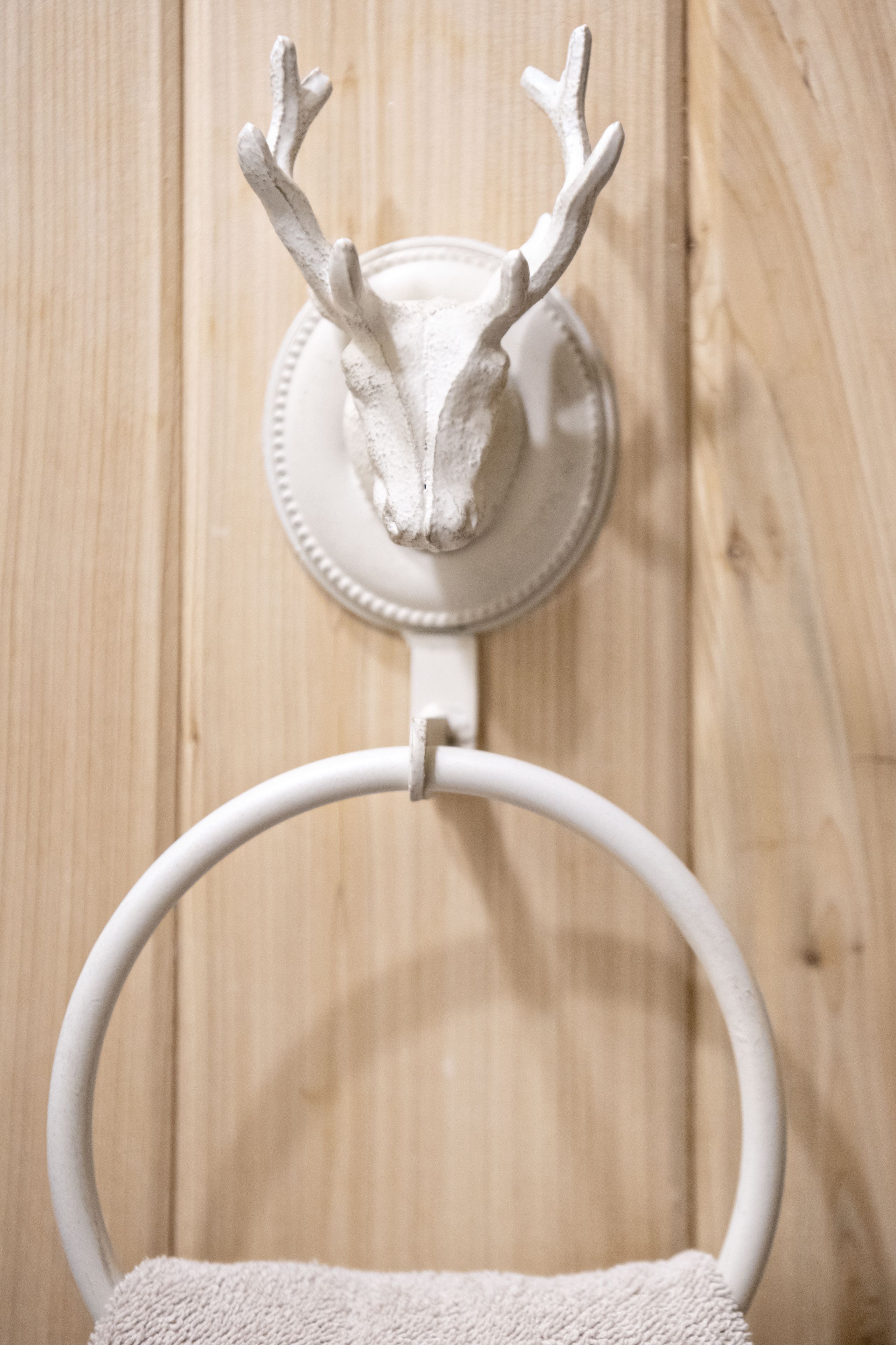 A wall-mounted deer head decoration above a white towel ring.